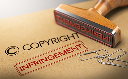 A light brown manilla folder labeled "Copyright" with "INFRINGEMENT" stamped in a bold red over it. Paper clips are scattered over the folder.