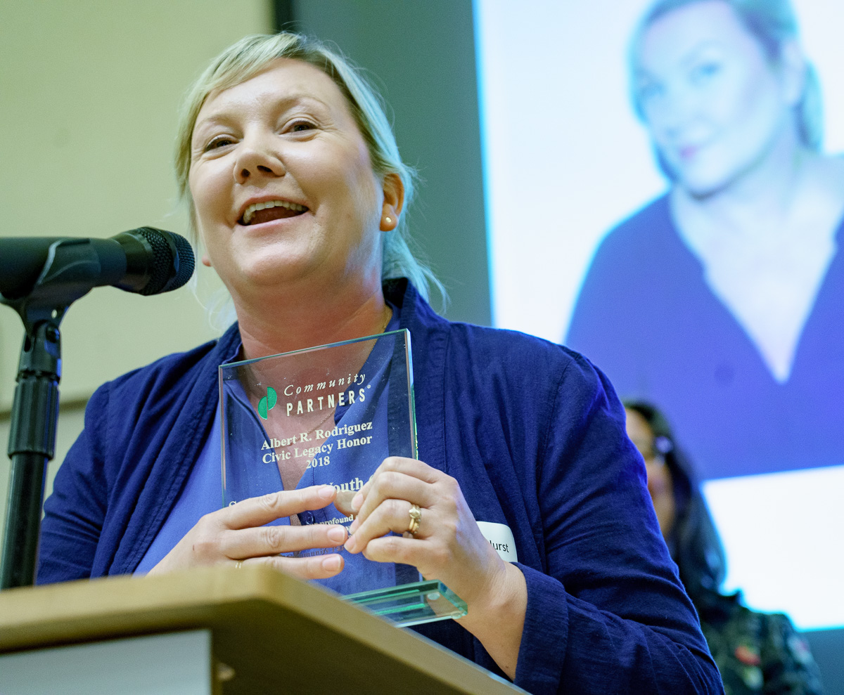 Alison Hurst, Executive Director of Safe Place for Youth smiles at the podium as she accepts the Al Rodriguez Civic Legacy honor