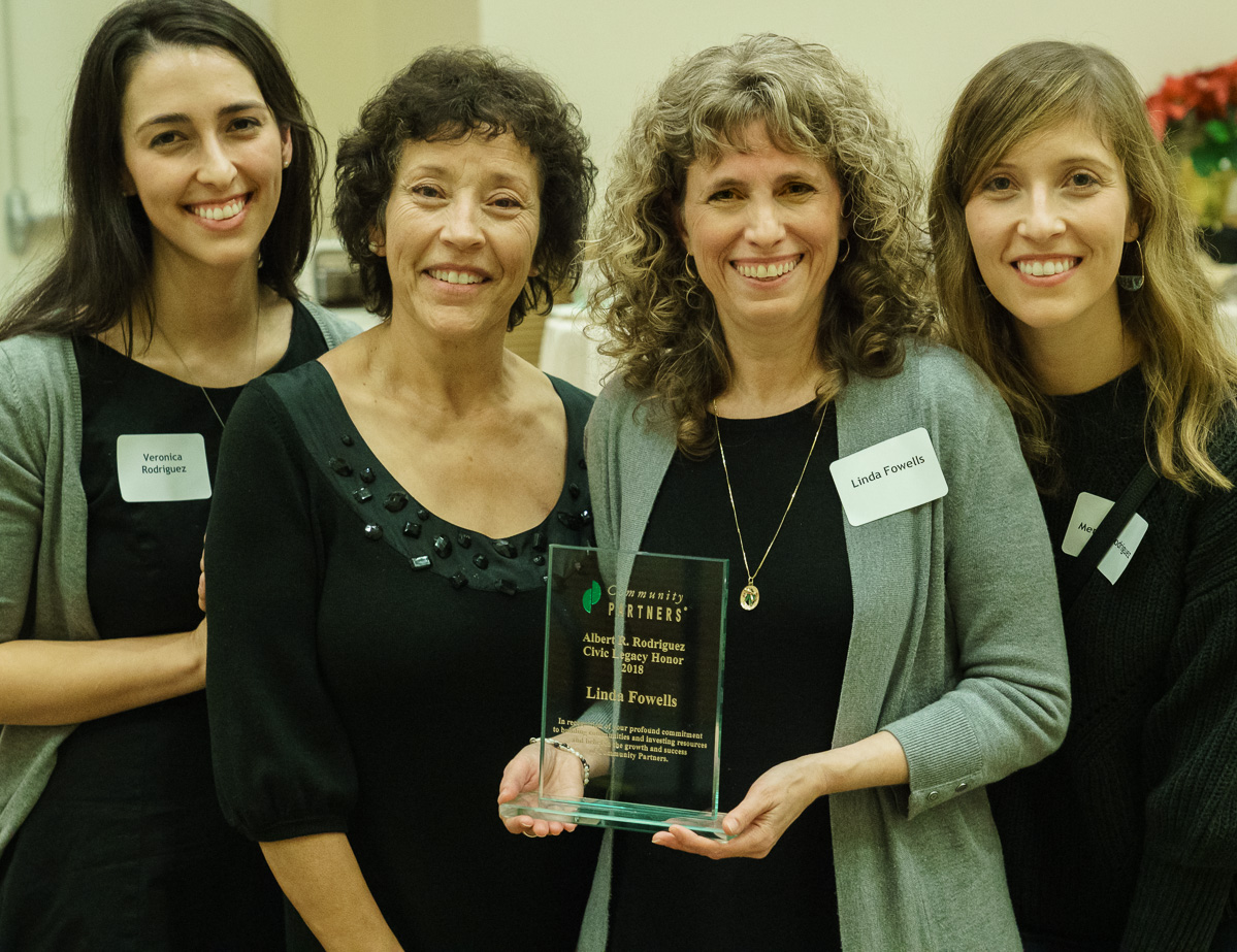 Exiting Vice President of Community Partners, Linda Fowells stands with her Al Rodriguez Civic Legacy Honor plaque proudly along with Al's personal legacy, his wife and two daughters.