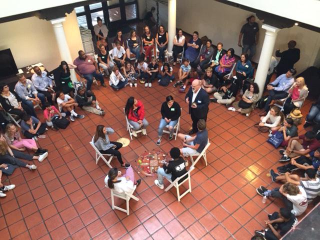 Folks sit in chairs in a circle to engage in "council"